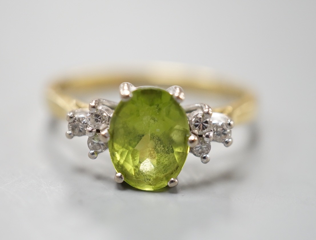 A modern 18ct gold and oval cut peridot ring, with diamond set shoulders, size M, gross weight 3 grams.